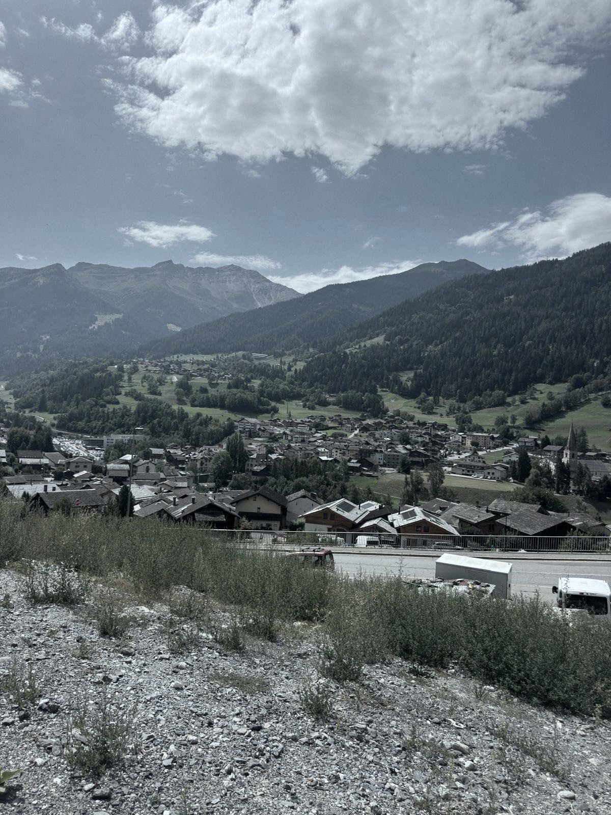Le bourg et son clocher au pied des versants, cadrage vertical depuis les hauts du village.